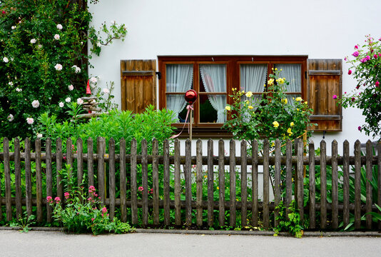 wiejski dom za drewnianym płotem, okna z drewnianymi okiennicami, r&oacute;że w wiejskim ogr&oacute;dku, biały dom z drewnianymi oknami, white country house, windows with wooden shutters, roses in a country garden