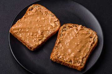 Nutritious sandwich consisting of bread and peanut butter on a black ceramic plate