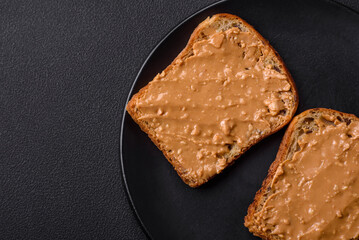Nutritious sandwich consisting of bread and peanut butter on a black ceramic plate