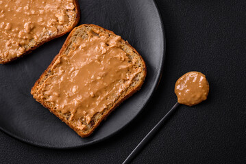 Nutritious sandwich consisting of bread and peanut butter on a black ceramic plate
