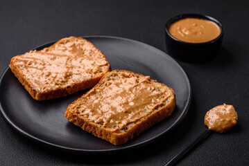 Nutritious sandwich consisting of bread and peanut butter on a black ceramic plate