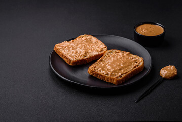 Nutritious sandwich consisting of bread and peanut butter on a black ceramic plate