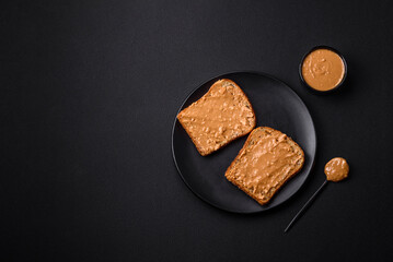 Nutritious sandwich consisting of bread and peanut butter on a black ceramic plate
