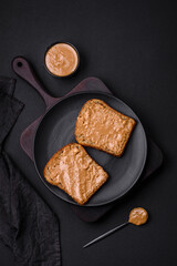 Nutritious sandwich consisting of bread and peanut butter on a black ceramic plate