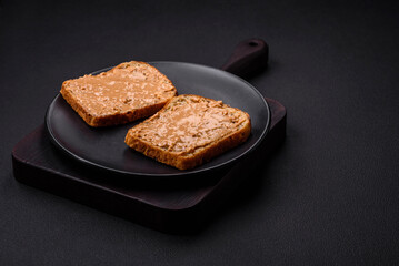 Nutritious sandwich consisting of bread and peanut butter on a black ceramic plate
