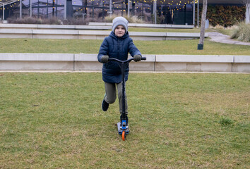 A boy rides a scooter in the park