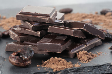 Broken dark chocolate and cocoa beans on a table