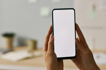 Minimal close up female hands holding smartphone with white screen mock up