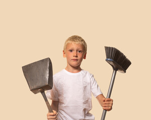 the boy is holding a dustpan and a sweeping brush. beige background