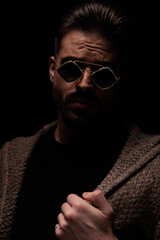 fashion model arranging his cardigan and looking at the camera