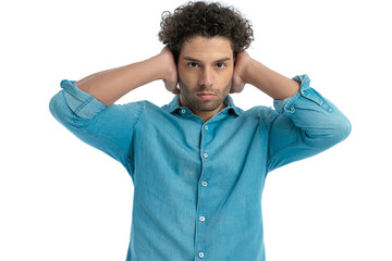 handsome man with curly hair in denim shirt covering his ears