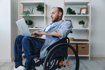A man in a wheelchair freelancer works at a laptop at home, work online, social networks and startup, copy space, integration into society, concept of health disabled person, real person close-up