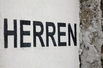 Black letters "Herren" on a white wall
German word for men, sign for gentleman toilets