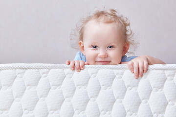 Baby on the bed mattress close-up. The sidewall of the mastras is stitched with finishing lines.