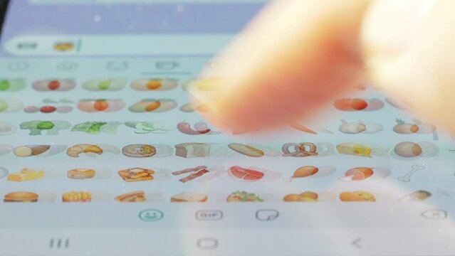 Macro finger browsing emojis on a virtual keyboard
