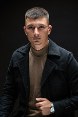 Young successful stylish man. Classical portrait of a businessman dressed in a jacket with a watch on his hand.