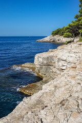 Fototapeta na wymiar Vertical View of Pula Rocky Beach in Europe. Beautiful Scenery of Stony Cliff with Blue Sky and Adriatic Sea in Croatia during Summer Day. 