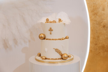 White luxury cake with gold decoration for baptism or birthday. Gold cross, balls and angel wings...