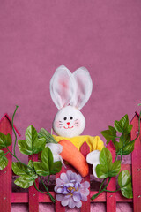 White Easter bunny decoration against pink background. White bunny and dark pink Easter decorations.