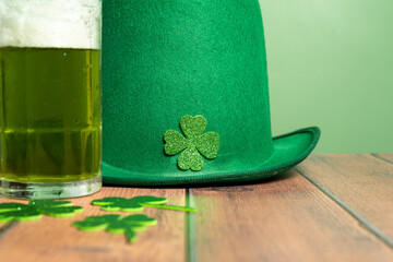 Green hat, shamrocks, coins and a mug of beer on the table. St. Patrick's Day. High quality photo