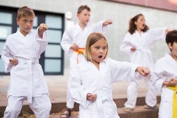Obraz na płótnie Canvas Young children in kimono perform techniques karate on a city street