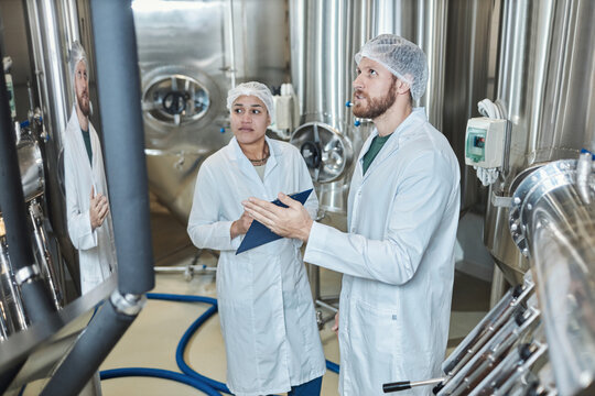 Two People Wearing Lab Coats Inspecting Food Factory Workshop