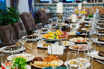 a large festive table with candles, snacks and tableware.