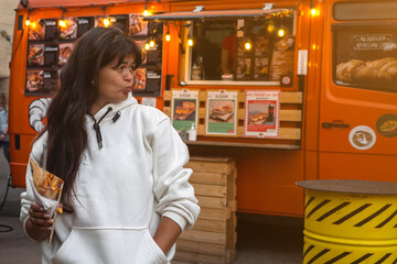 woman with Belgian french fries with sauce at street food festival. food truck on blurred background
