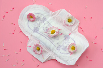 menstrual pad on a pink background and flowers close up © Viktoriia Kolosova