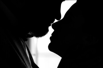 Close portrait of two lovers close together. Silhouettes of a kiss on a white background. Lips close up. Black and white photo