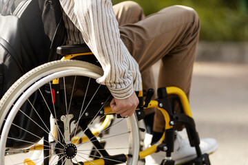 Close-up of male hand on the wheel of a wheelchair.
