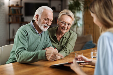 Happy senior couple having a meeting with their insurance agent at home
