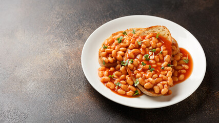 Baked beans on toast in tomato sauce on white plate