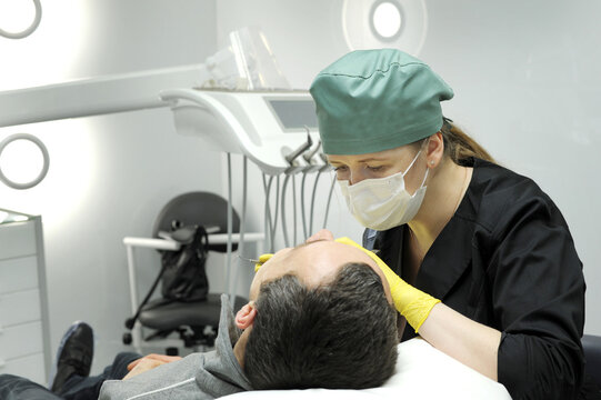 European mid pleased dentist woman in face mask working in dental clinic. High quality photo