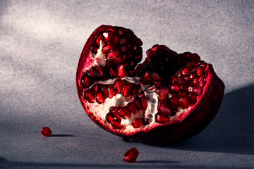 Half of a ripe pomegranate on a light gray background. Seasonal winter fruits. Source of iron.