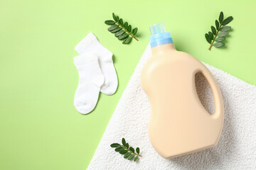 Laundry detergent gel bottle with green leaves and baby's socks on towel.