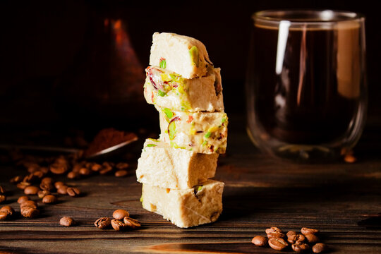 Halva with pistachios. Traditional oriental sweets. Fresh coffee, copper cezve and coffee beans on background. Jewish, Turkish, Arabic oriental national dessert. Turkish delight concept.
