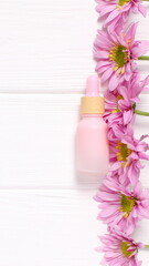 Obraz na płótnie Canvas Cosmetic bottle on wooden table with pink daisy flowers