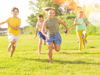 Portrait of five smiling preteen kids running in race and laughing in park