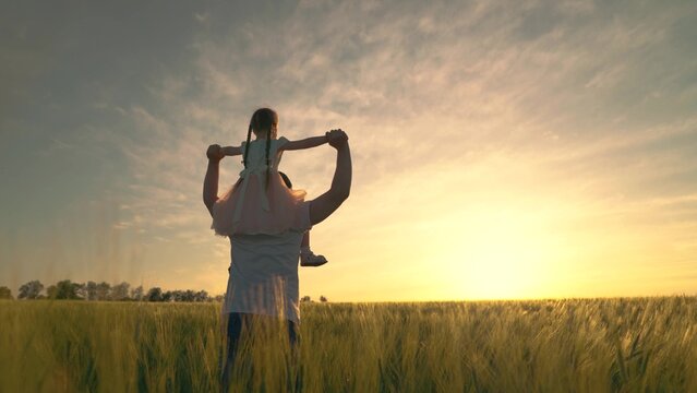 Happy Child And Father Are Playing In Field Of Ripening Wheat. Little Daughter On Fathers Shoulders. Baby Boy And Dad Travel On Field. Kid And Parent Play In Nature. Happy Family And Childhood Concept