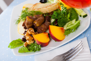 Portion of salad with fried chicken hearts, grilled cheese, ripe pear, peach and greens