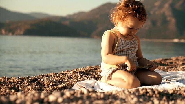 Unhappy little girl uses smartphone on the beach. Travel apps and new user concepts