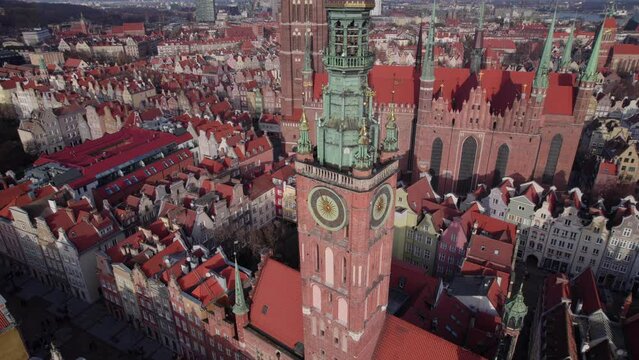 Top down aerial shot of ancient cathedral and clock tower in European town with tiled red roofs, 4k
