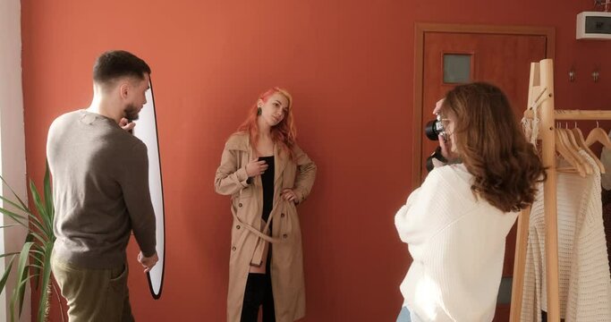 Process of a photo session in the studio, female photographer with male assistant taking pictures of fashion model