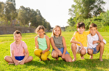 Fototapeta premium Portrait of five smiling friends kids posing in a park at summer day during school weekend