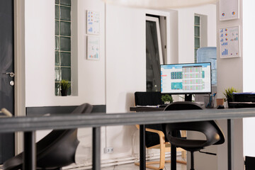 Financial sales report on the desktop computer monitor, printed charts on the table for the next day meeting. Empty workstations in office before beginning work schedule.