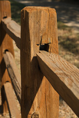 Details of a notched wooden fence post with rails in bright sun light
