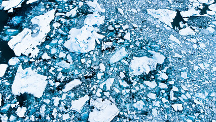 Melting Arctic ice in ocean water. Blue glacier ice covered with snow in Iceland. Global warming and climate crisis. Pure antarctic landscape aerial view.