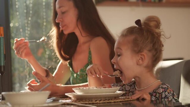 Beautiful woman and her daughter have healthy breakfast at home