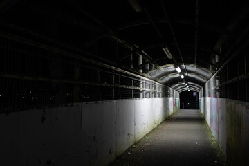 Illuminated empty walkway at night lit by lights above